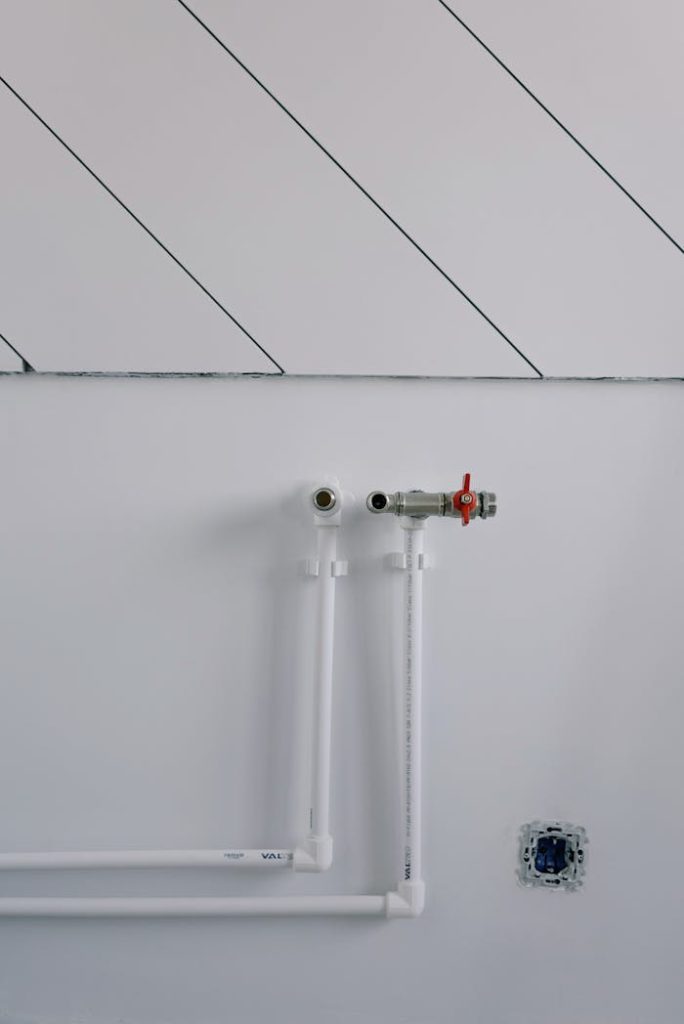 pipes-of-radiator-in-empty-room-5691473 White wall with minimalist plumbing pipes and diagonal lines